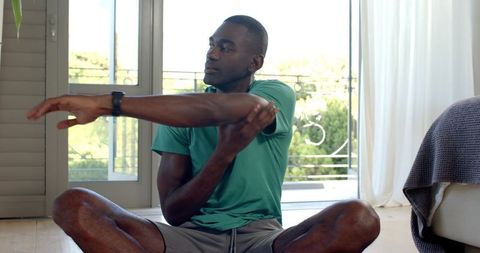 African american man stretching shoulder in home workout wearing sportswear