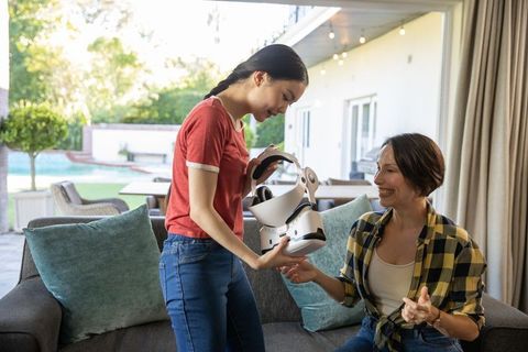 Mother and Daughter Sharing VR Headset in Relaxing Lounge Room