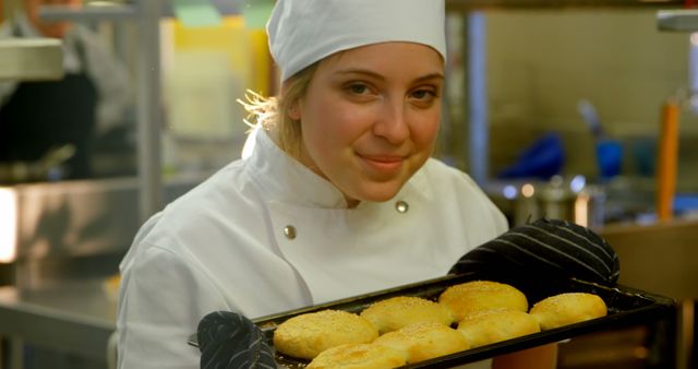 Female Chef Holding Tray of Freshly Baked Buns in Professional Kitchen - Download Free Stock Images Pikwizard.com