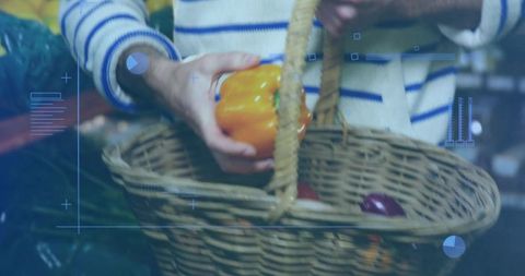 Man selecting orange bell pepper holding wicker basket at farmers market with hud overlay
