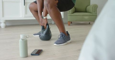 Home kettlebell workout man performing squat and hinge with 5kg kettlebell in living room