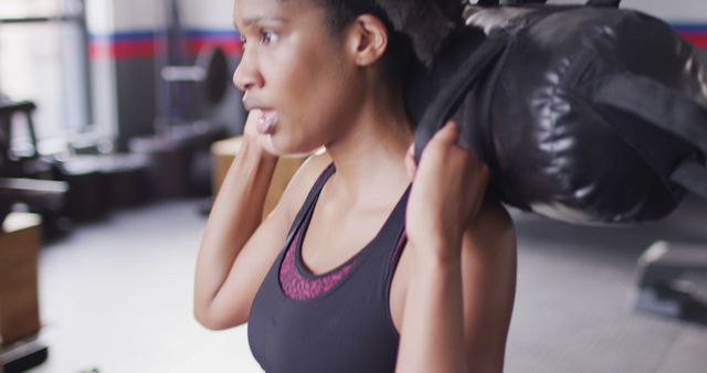 Image of determined african american woman working out with weights at a gym. Exercise, fitness and healthy lifestyle.
