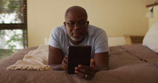 Older Man Reading Tablet While Lying on Bed in Relaxed Setting - Download Free Stock Images Pikwizard.com