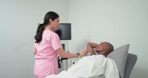 Female clinician performing breast ultrasound on reclining african woman in clinic