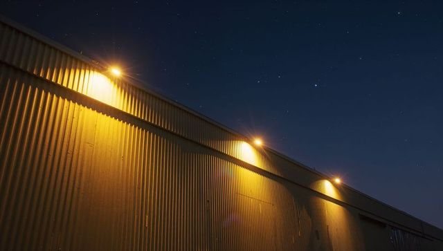Modern Industrial Building Illuminated by Evening Lights Under Starry Sky