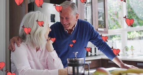 Happy Senior Couple Enjoying Coffee with Heart Graphics in Kitchen