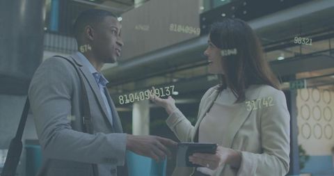 Business colleagues discussing analytics and collaboration in modern office atrium