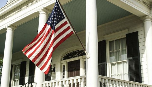 Southern colonial porch with american flag fluttering from column-mounted pole