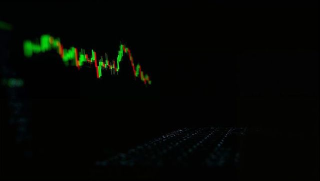 Glowing candlestick trading chart over backlit keyboard in dark financial workspace