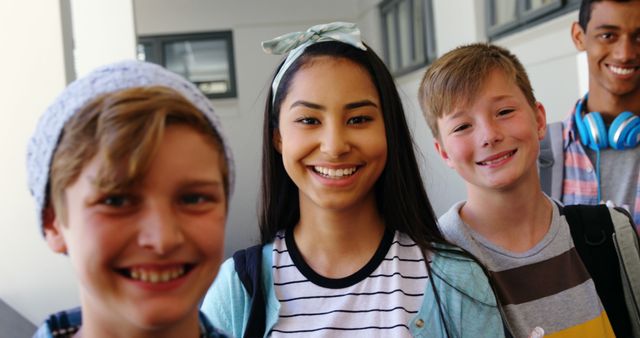 Portrait of smiling students standing with notebook in corridor at school