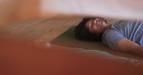 Man practicing mindful breathing on yoga mat in home studio, relaxed restorative session