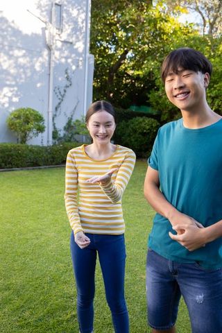 Asian Friends Enjoying Casual Outdoor Gathering on Sunny Lawn