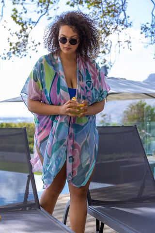 African american woman poolside holding lemon drink wearing sunglasses and floral cover-up