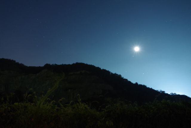 Crescent moon and faint stars shining over hills, creating a tranquil and peaceful scene. Ideal for use in nature-themed projects, relaxation promotions, astronomy, night-time landscapes, and outdoor adventure content.