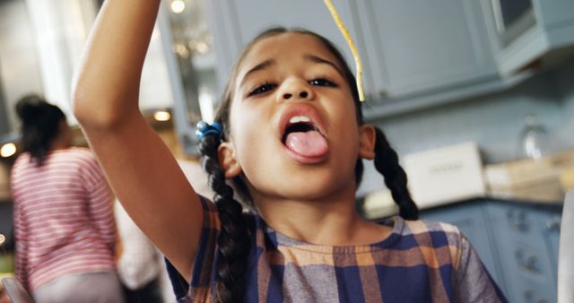 Young Girl Playing with a Spaghetti Strand in Kitchen - Download Free Stock Images Pikwizard.com