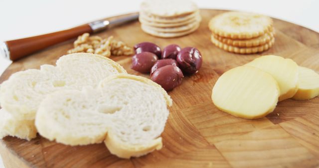 Slices of bread, different cheeses, olives, and crackers served on a wooden board, ideal for gourmet presentations, party trays, and social gatherings.