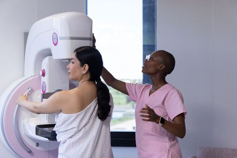 Hispanic woman receiving mammogram from african american technologist during breast screening