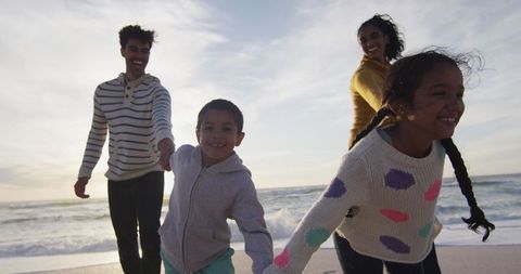 Happy Family Walking on Beach at Sunset