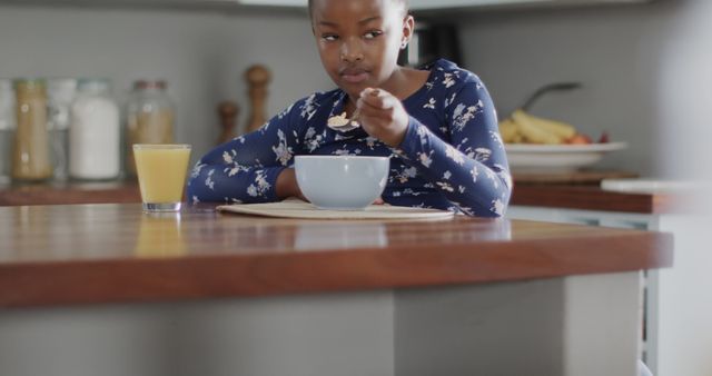 Young girl eating breakfast at kitchen table - Download Free Stock Images Pikwizard.com