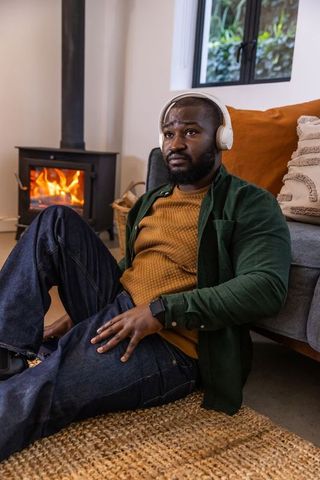 African american man relaxing by wood stove listening to music with headphones