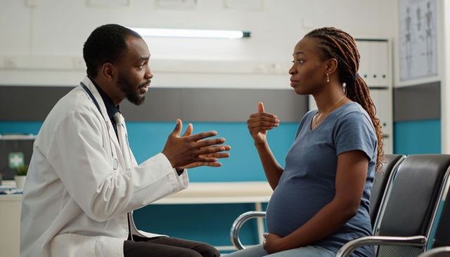 Doctor consulting expectant mother in clinic discussing prenatal care and health concerns