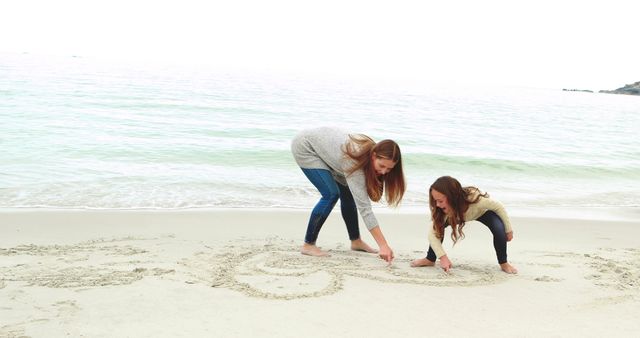 Two Women Writing In The Sand At Seaside - Download Free Stock Images Pikwizard.com