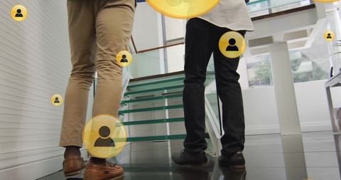 Business colleagues ascending office stairs with digital media icons