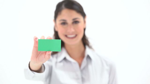 Young woman holding a green card while smiling, isolated against a white background. This is perfect for advertising, business presentations, promotional material, or social media content. The bright green card can be customized with logos, text, or designs.