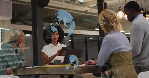 Multicultural team collaborating with tablet and laptop in modern coworking space