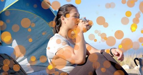 Woman Enjoys Authentic Beach Camping Experience with Hot Beverage