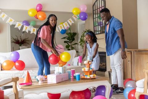African american family celebrating birthday arranging balloons cupcakes and wrapped gifts