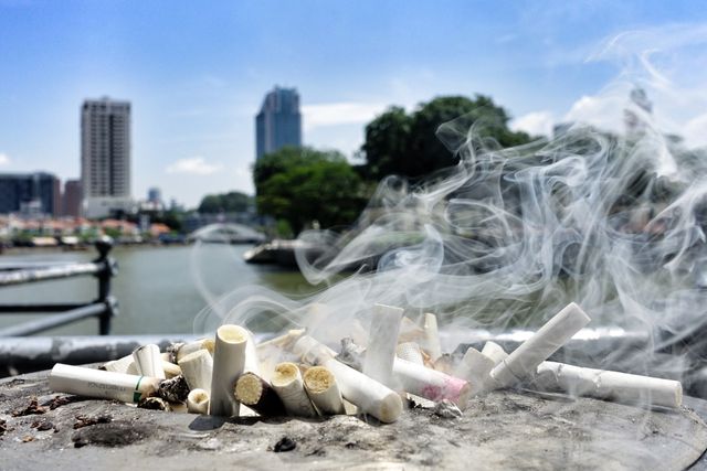 Smoking cigarettes on a surface with a blurred cityscape in the background. The scene highlights the issue of pollution and litter in urban environments. Suitable for concepts related to smoking, environmental pollution, public health awareness campaigns, and the impact of human habits on city settings.