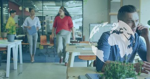 Businessman talking on phone in open-plan office with digital globe overlay