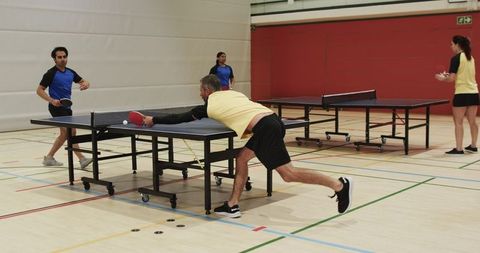Diverse Adult Players Engaging in Singles Table Tennis Matches in Sports Hall
