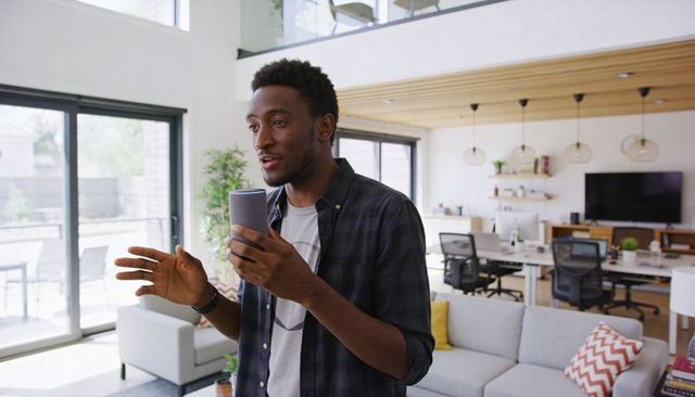 Man presenting with smartphone in bright modern home office loft for remote work and livestream