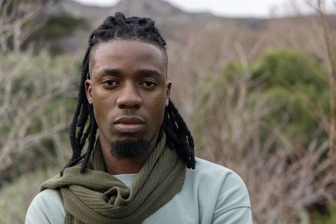 African american man standing on hillside wearing olive scarf and light green sweatshirt