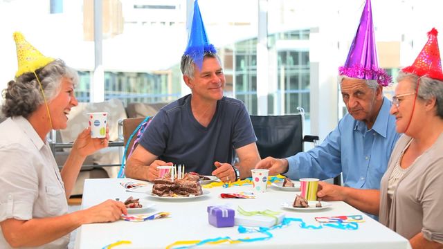 A group of seniors enjoying a joyful birthday celebration together, wearing colorful party hats and sharing a delicious cake. This lively image can be used for promoting senior community events, advertising birthday party services for elderly people, or illustrating articles on social engagement among seniors.