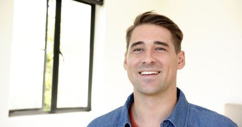 Smiling Man in Bright Room Wearing Denim Shirt