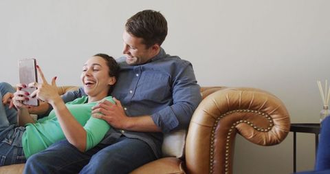 Cheerful Couple Relaxing Together with Tablet on Comfortable Sofa