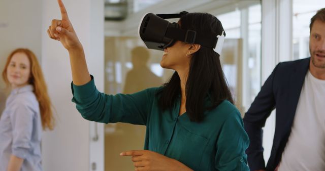 Individuals are engaging with virtual reality technology in a modern office. This could be used to illustrate innovation in the workplace or teamwork and collaboration in a technology-driven setting.