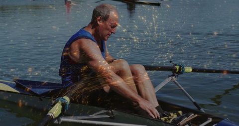 Senior rower adjusting foot straps on river scull