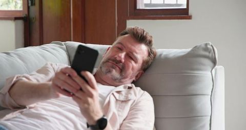 Man Relaxing on Sofa Using Smartphone in Cozy Living Room