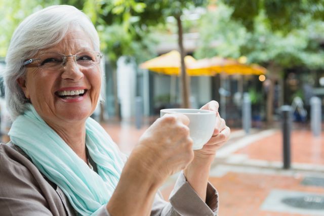 Senior woman holding a coffee cup in outdoor cafe