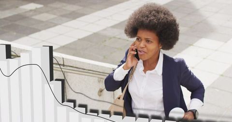 Climbing professional woman talking on smartphone while ascending urban concrete steps