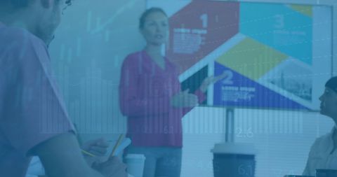 Businesswoman presenting colorful data projections to attentive colleagues in a contemporary office meeting room. The office setup showcases teamwork, leadership, and effective data analysis. Suitable for use in depicting corporate environments, collaboration scenes, and professional growth materials.