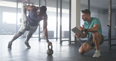 Personal trainer guiding fit man in kettlebell workout