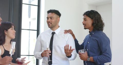 Young professionals networking with champagne at sunlit modern cocktail gathering