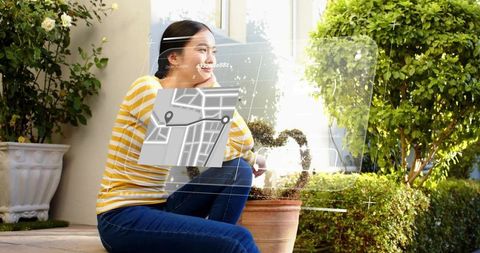 Young woman viewing augmented reality map on sunlit garden patio, relaxed tech lifestyle