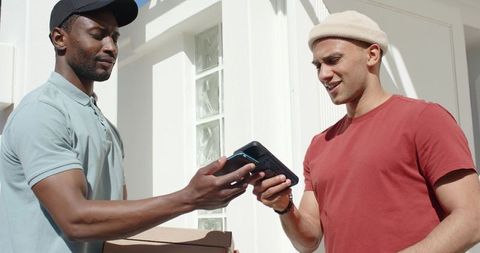 Courier Delivering Parcel While Recipient Paying with Mobile POS on Sunny Residential Porch