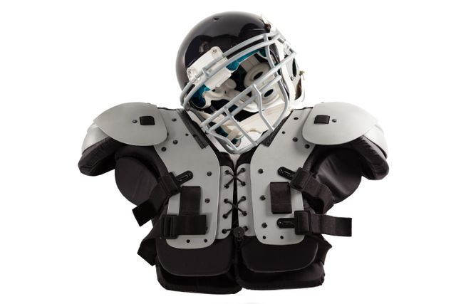 Close up of American football helmet and shoulder pads against white background. Ideal for use in sports-related articles, advertisements for sporting goods, safety gear promotions, and athletic training materials.